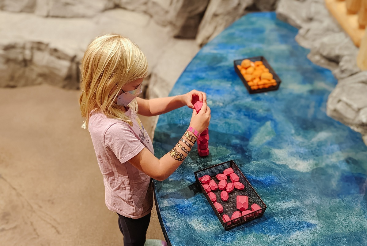 A girl plays with colorful rocks at Imagine Children's Museum's newly expanded exhibit area